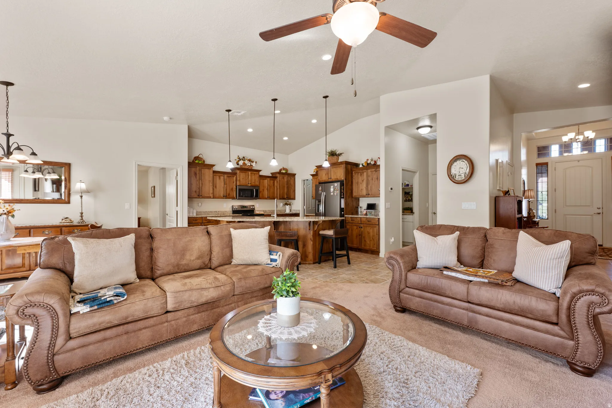 Living room with a chandelier, vaulted ceiling, a ceiling fan, light carpet, and recessed lighting