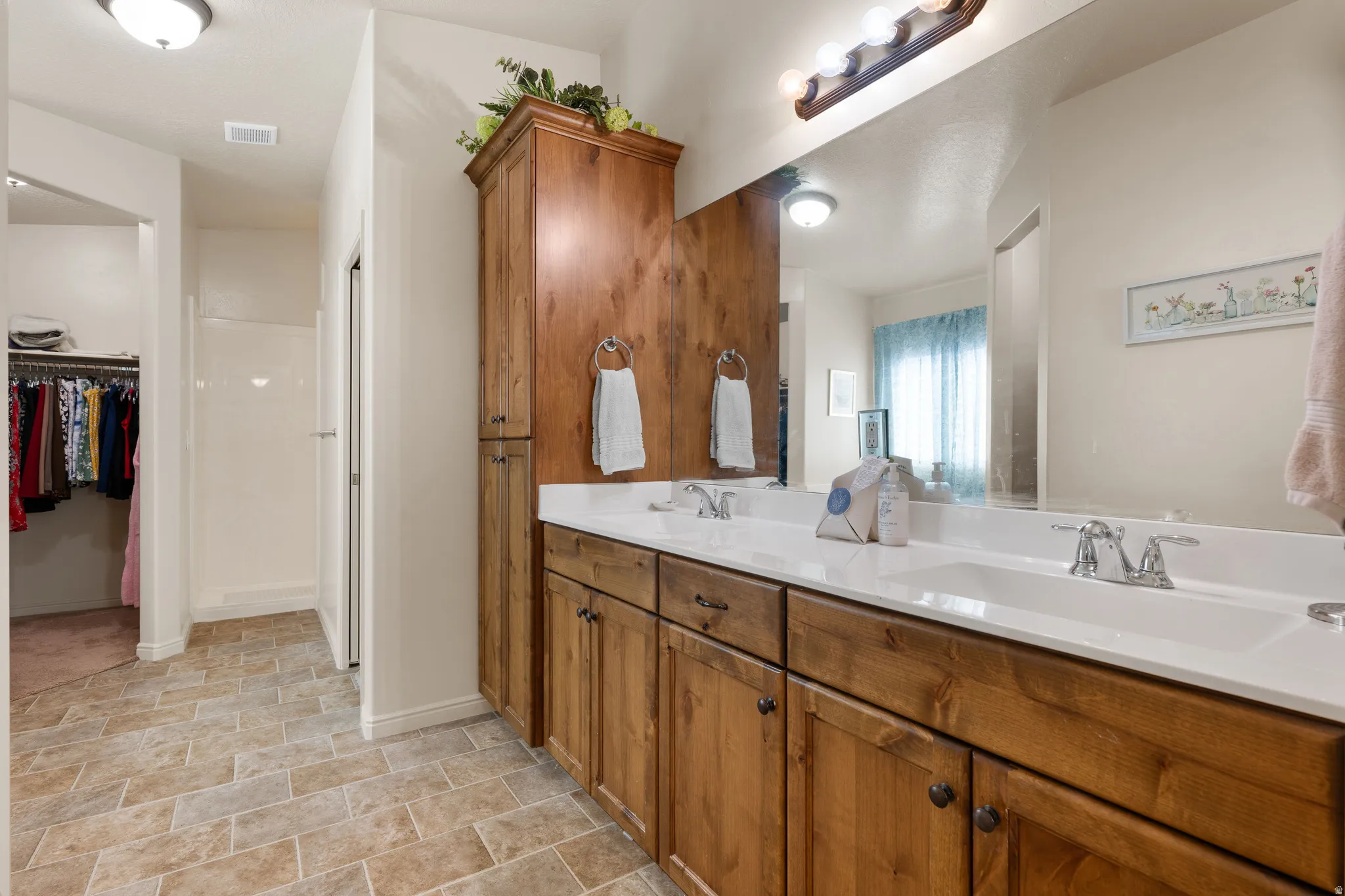 Bathroom with double vanity and a walk in closet