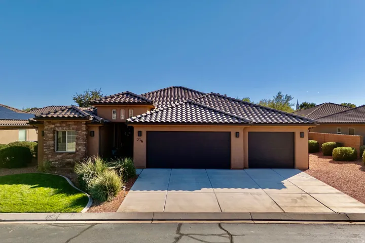 View of front facade featuring stucco siding, driveway, an attached garage, and a tiled roof