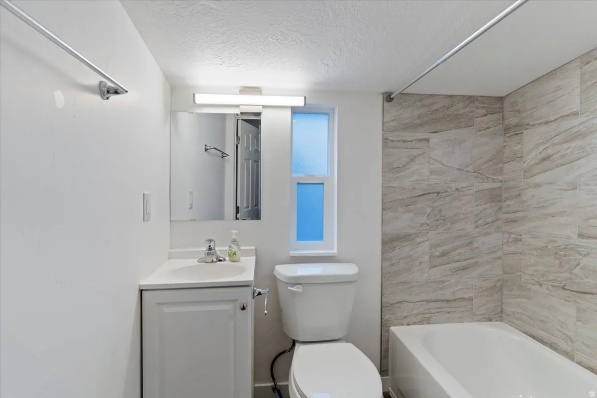Full bath featuring a textured ceiling, vanity, and  shower combination