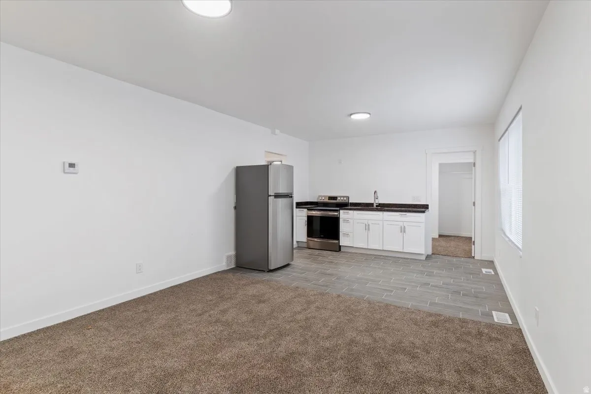 Kitchen featuring dark countertops, stainless steel appliances, white cabinets, and wood finish floors
