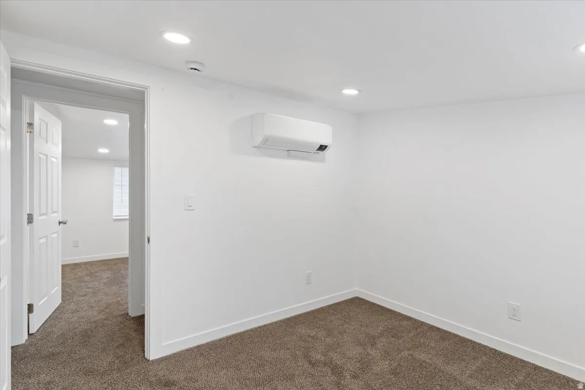 Spare room with dark colored carpet, recessed lighting, and a wall mounted air conditioner