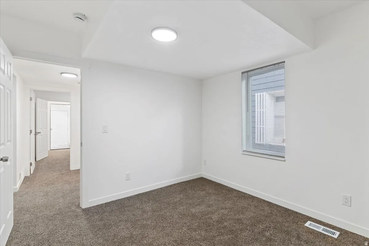 Spare room with dark colored carpet and baseboards