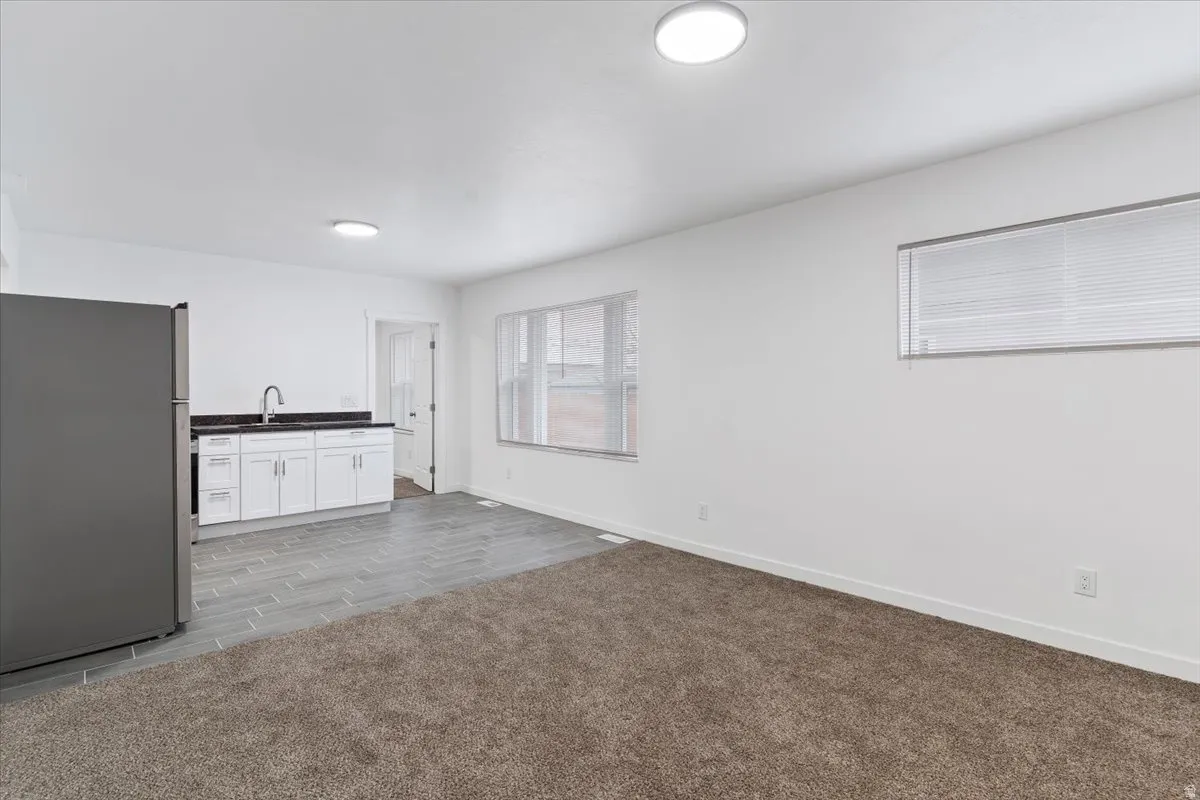 Interior space featuring dark countertops, freestanding refrigerator, white cabinetry, and wood tiled floors