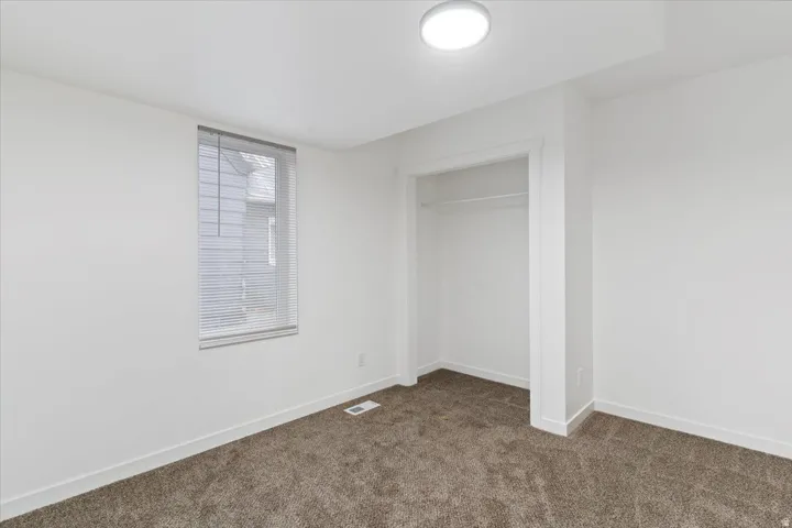 Unfurnished bedroom with dark carpet and a closet