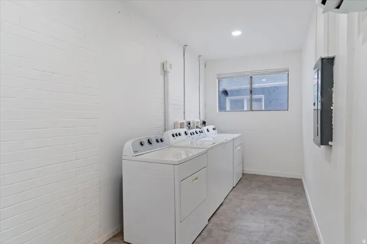 Washroom with separate washer and dryer, electric panel, and brick wall