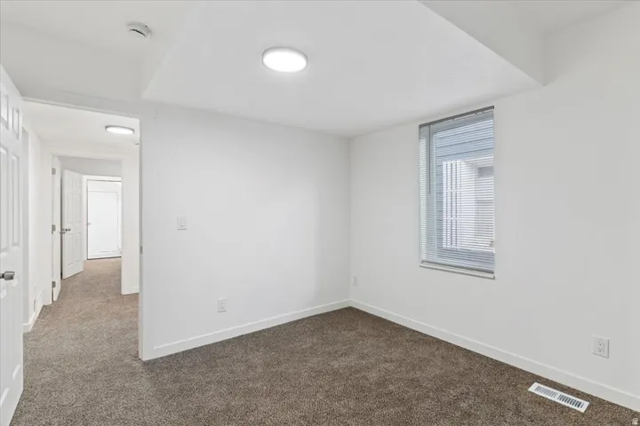 Spare room with dark colored carpet and baseboards