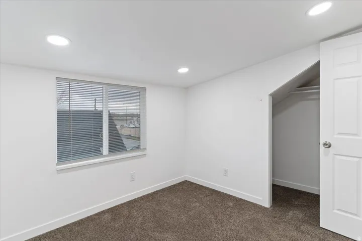 Empty room featuring dark colored carpet and recessed lighting