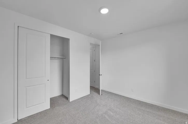 Unfurnished bedroom featuring light colored carpet and a closet