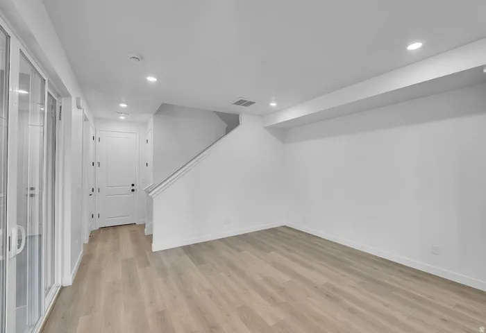 Basement featuring light wood-style floors, recessed lighting, and stairs