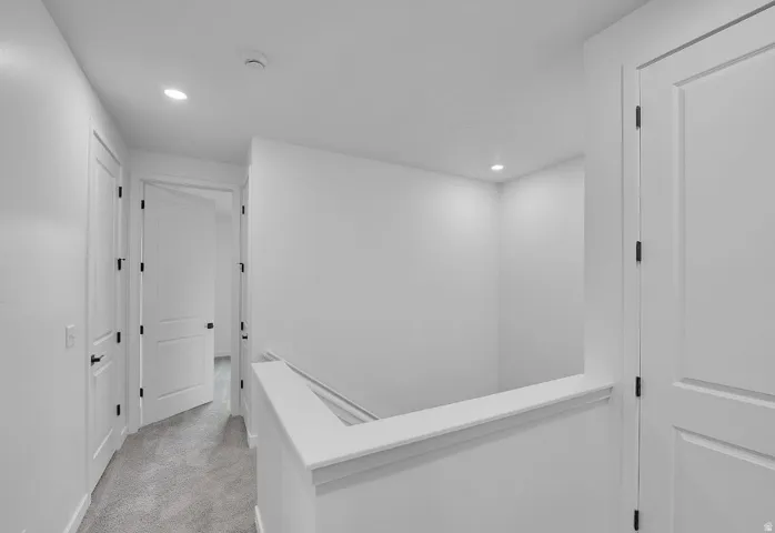 Hall featuring light colored carpet, an upstairs landing, and recessed lighting
