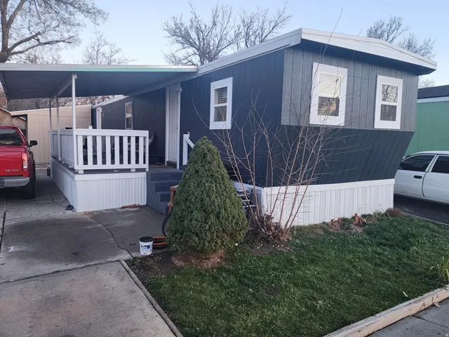 View of side of property featuring covered porch and a lawn