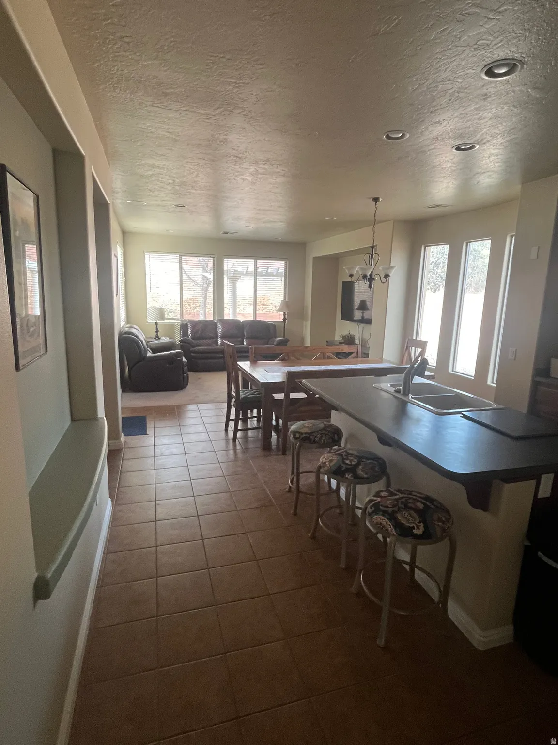 Dining space with a textured ceiling, a chandelier, healthy amount of natural light, and dark tile patterned flooring