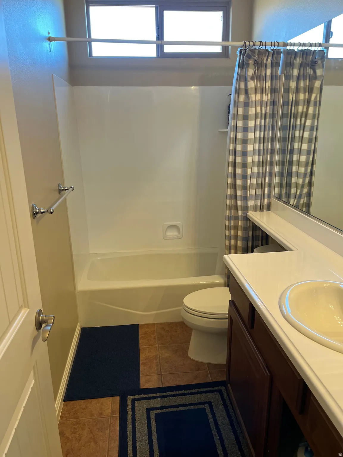 Bathroom with healthy amount of natural light, vanity, dark tile patterned floors, and shower / bathtub combination with curtain