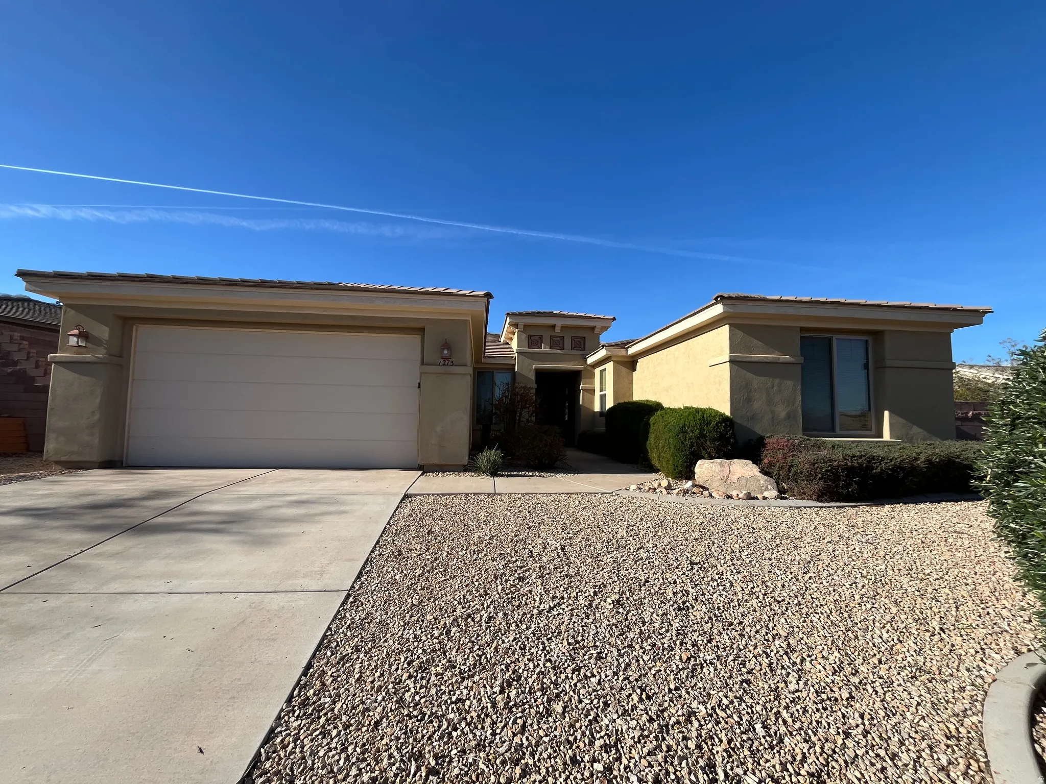 View of front of home featuring stucco siding, concrete driveway, a tiled roof, and a garage