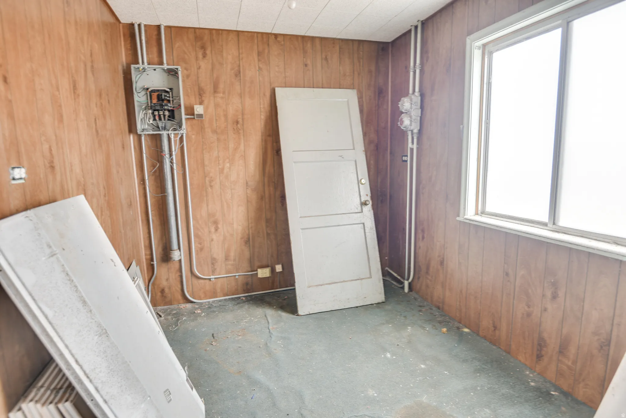 Misc room with wood walls, plenty of natural light, and electric panel
