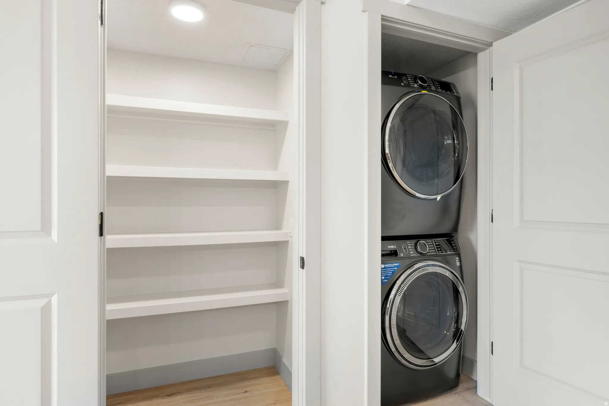 Laundry room featuring estacked washer and dryer and light wood-type flooring