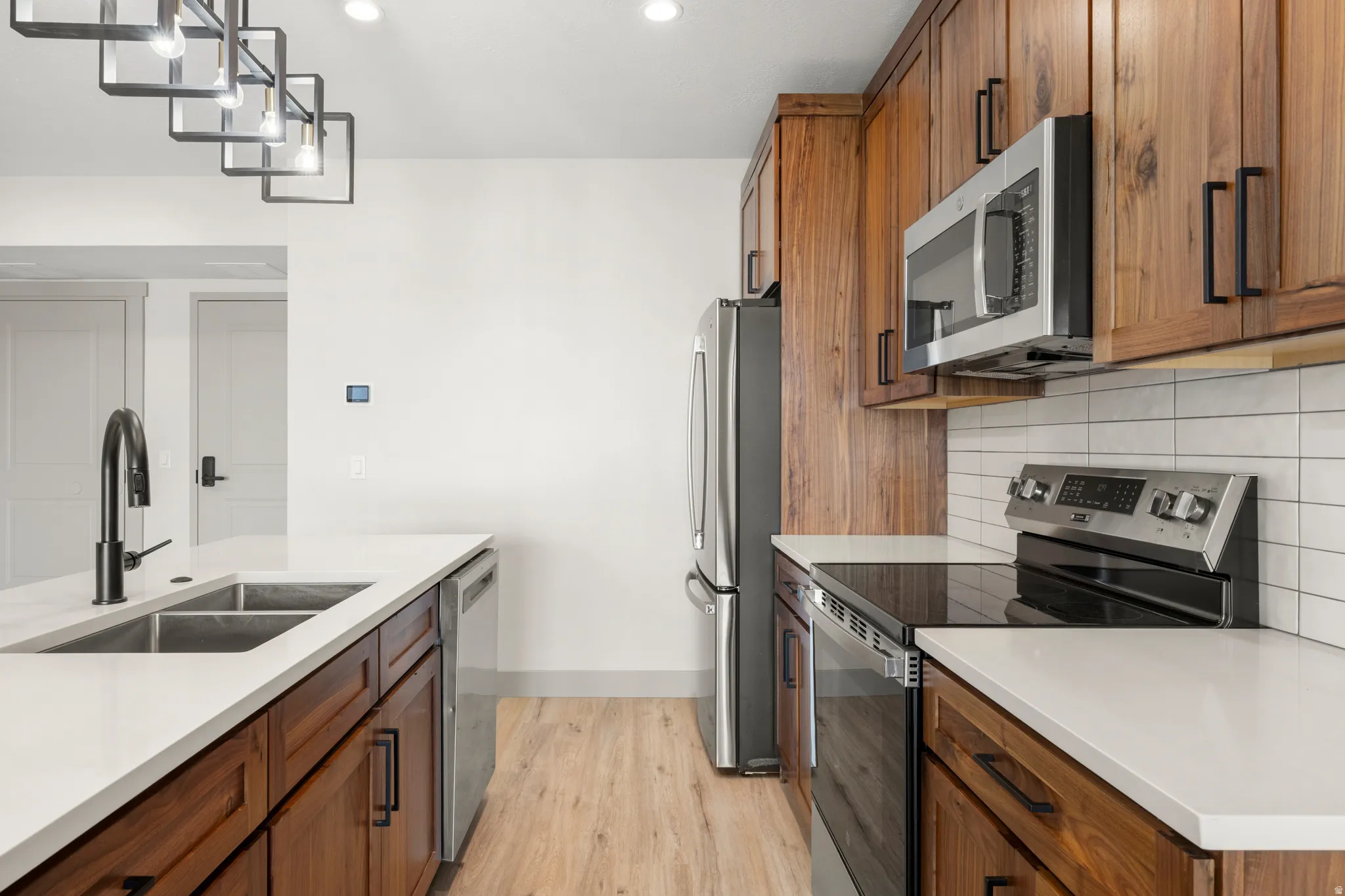 Kitchen featuring brown cabinets, stainless steel appliances, decorative backsplash, light wood-style flooring, and recessed lighting