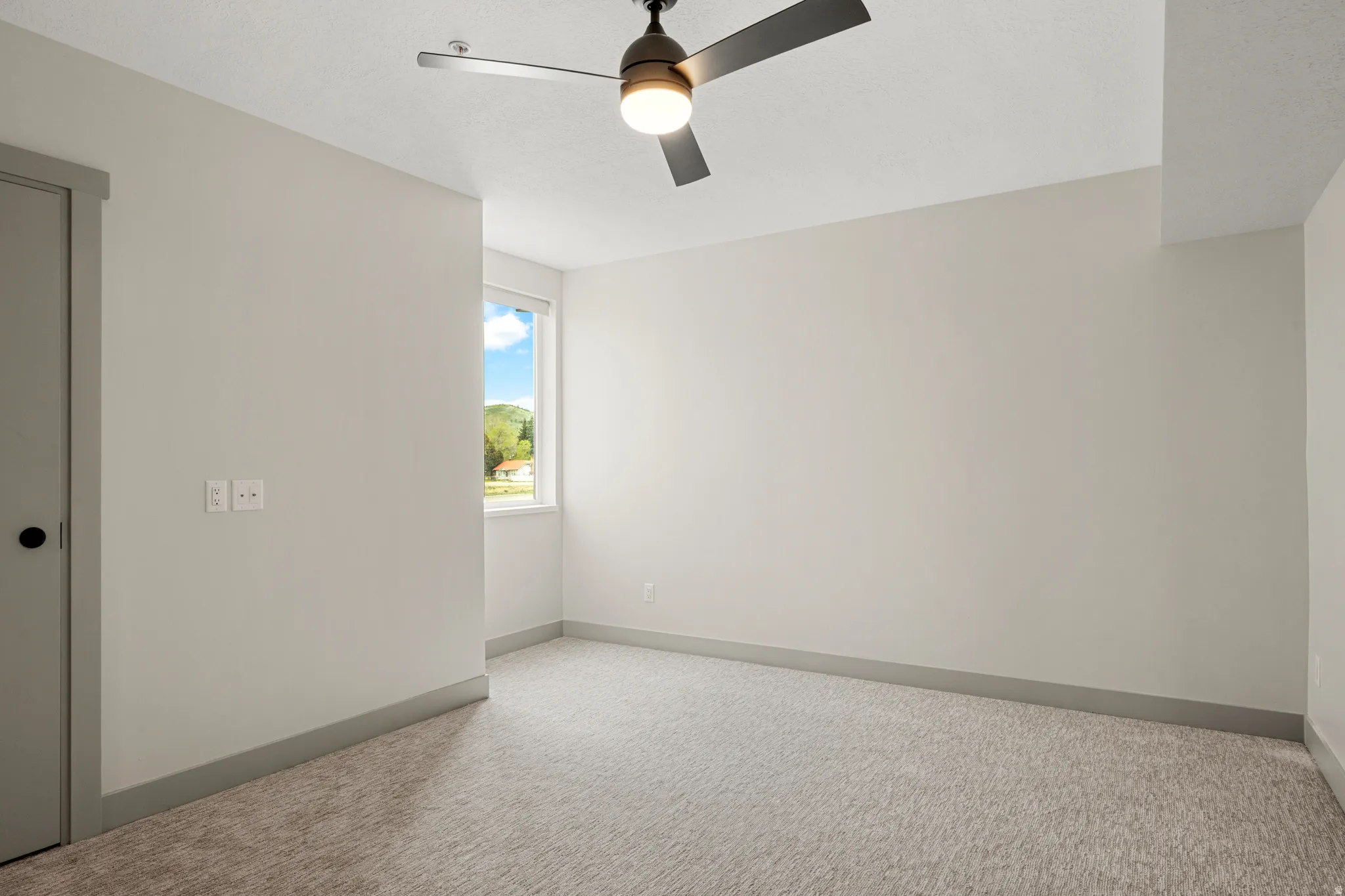 Carpeted spare room with baseboards and a ceiling fan