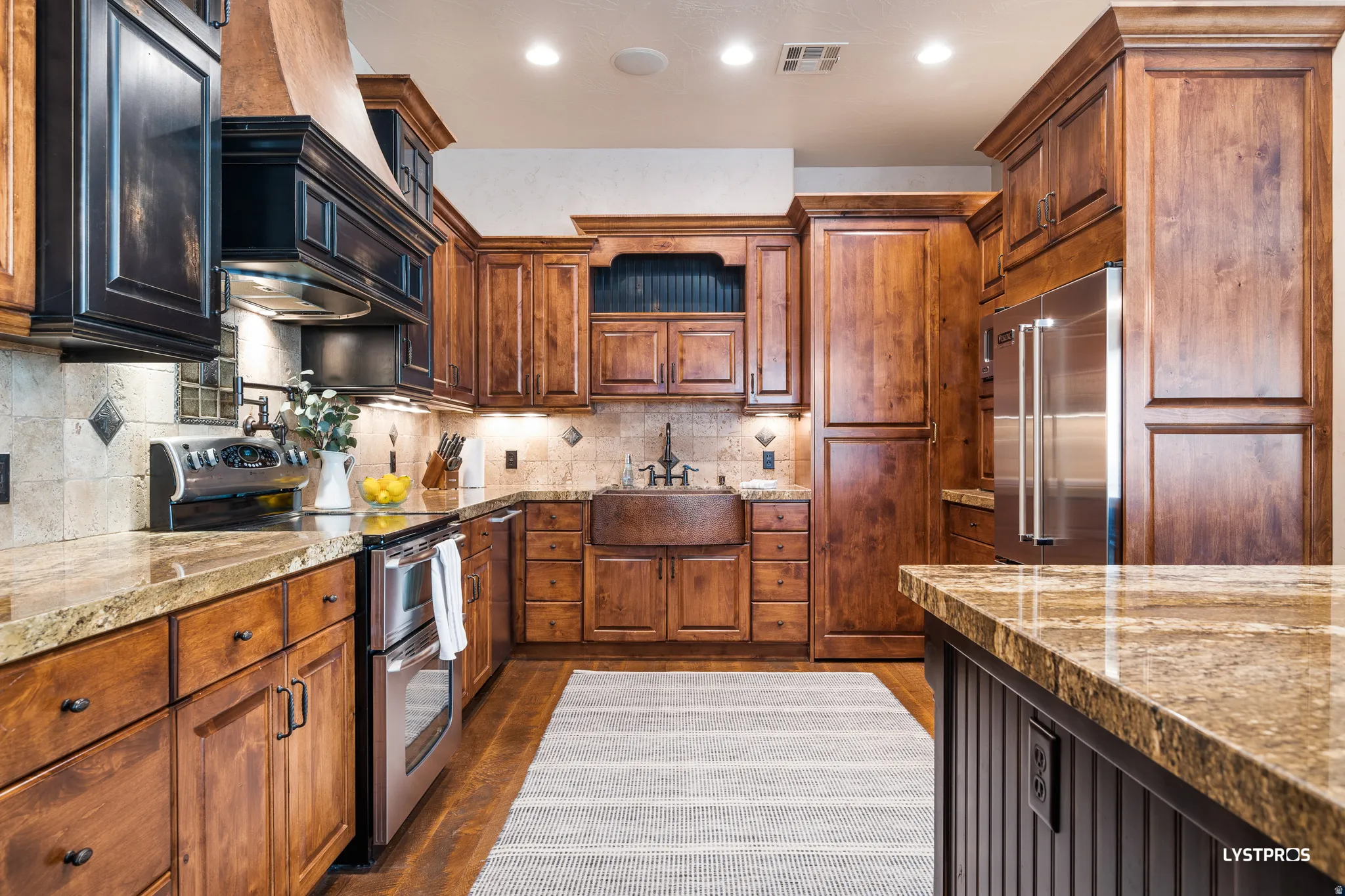Kitchen with appliances with stainless steel finishes, light stone countertops, custom exhaust hood, dark wood-style flooring, and recessed lighting