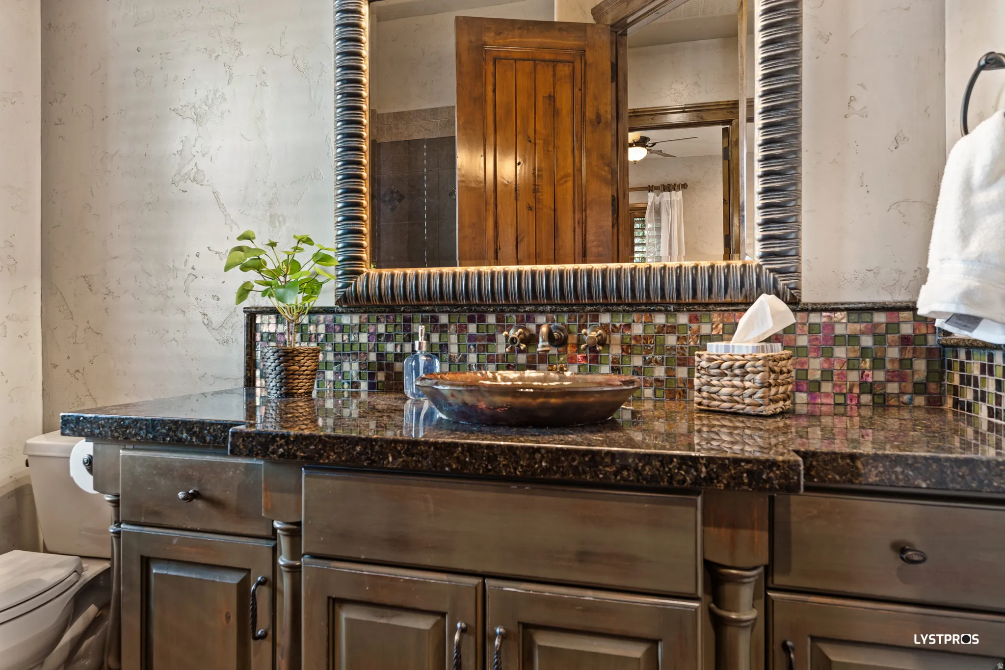 Bathroom featuring vanity, decorative backsplash, ceiling fan, and a textured wall