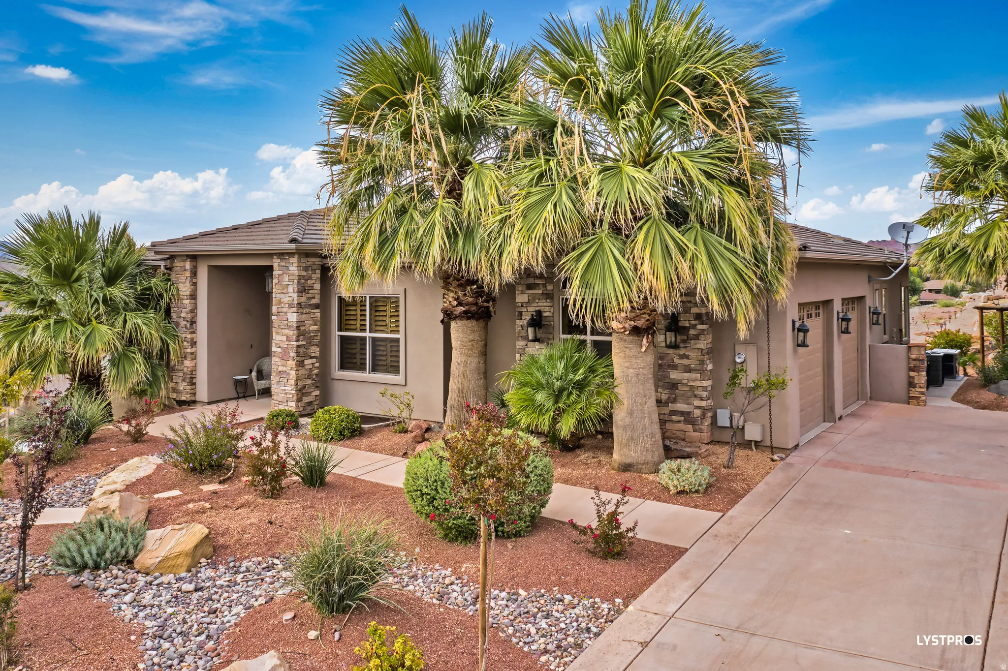 View of front of home featuring stucco siding, concrete driveway, and stone siding