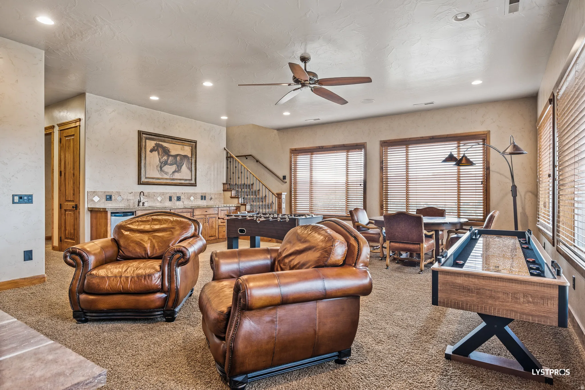 Carpeted living area with ceiling fan, recessed lighting, and a textured wall