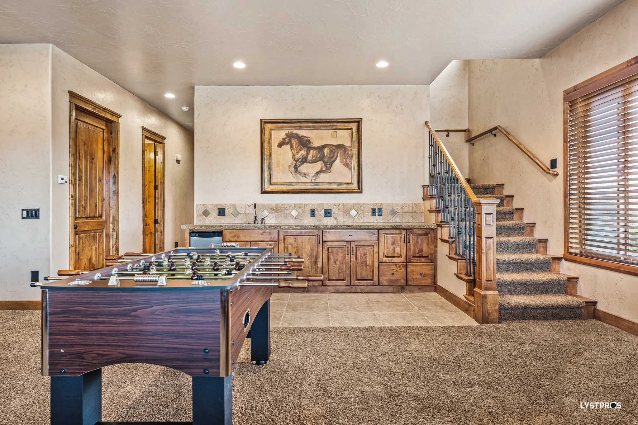 Rec room with a textured wall, light carpet, recessed lighting, and light tile patterned floors