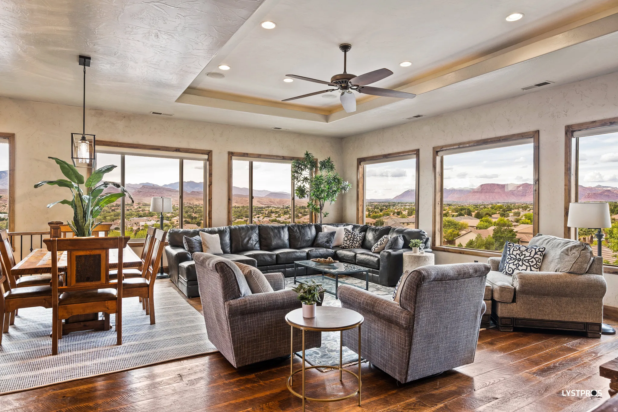 Living area with a raised ceiling, a mountain view, dark wood-style flooring, ceiling fan, and recessed lighting