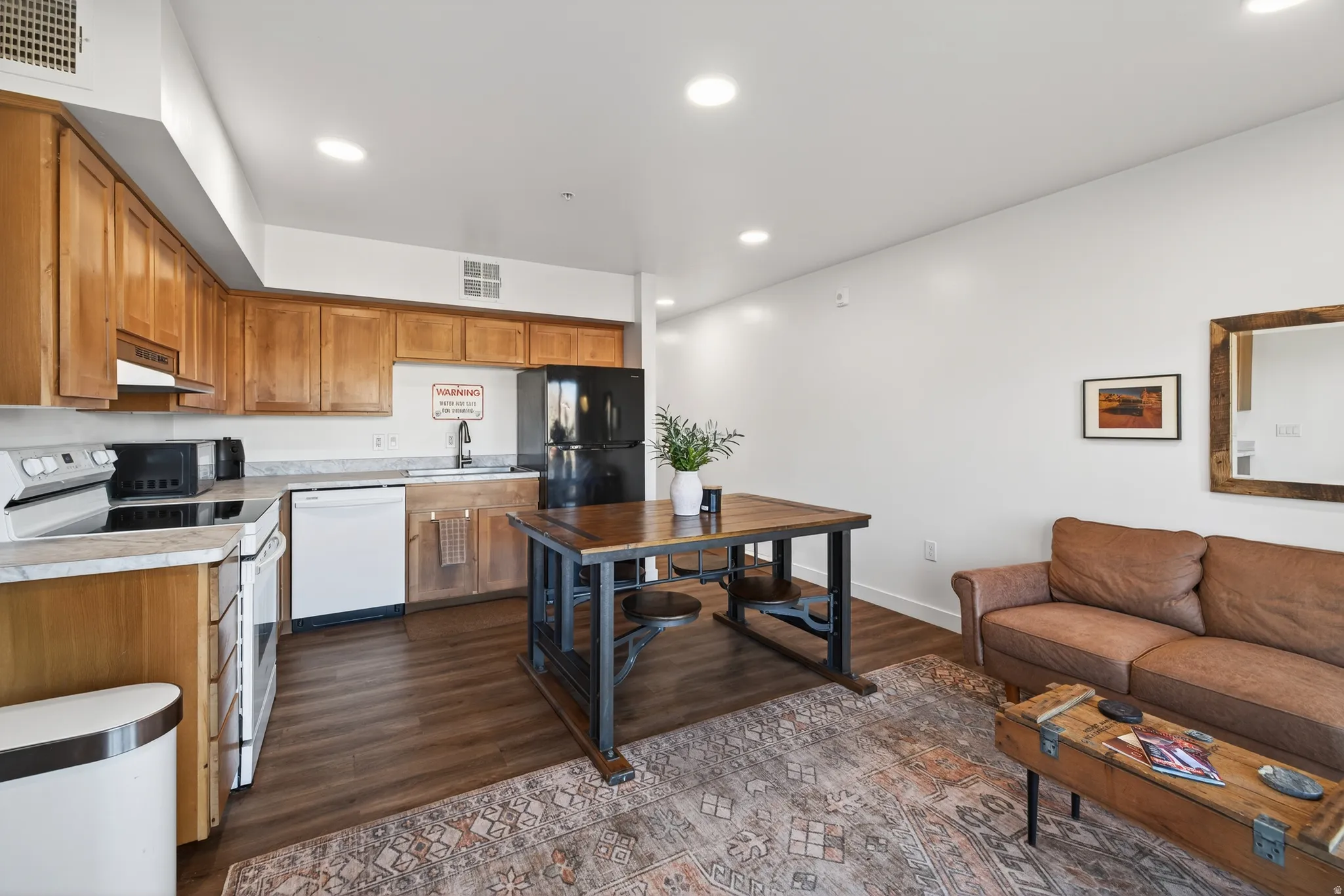 Kitchen with brown cabinets, black appliances, light countertops, recessed lighting, and dark wood-style floors