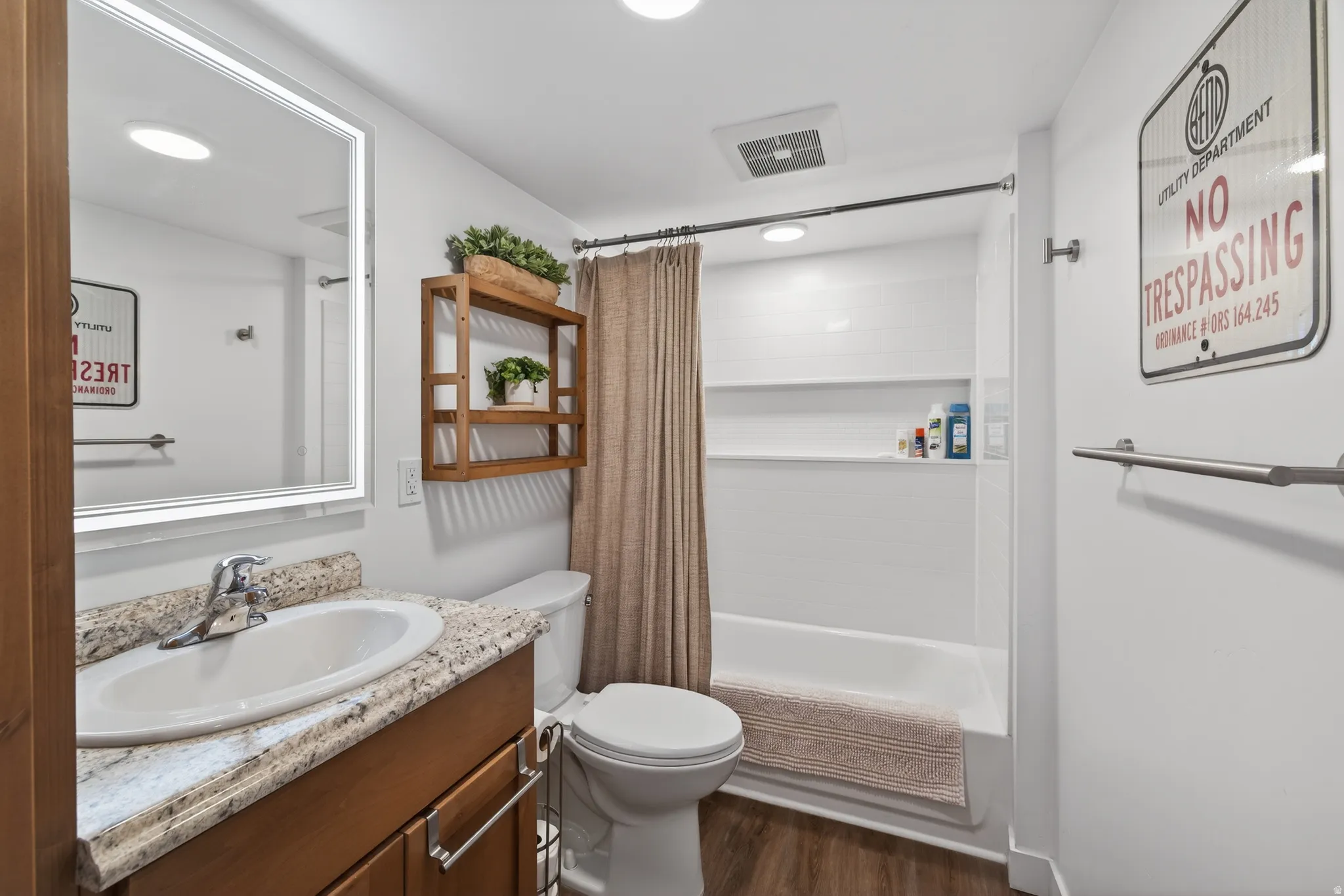 Full bath with shower / bath combination with curtain, vanity, and dark wood finished floors