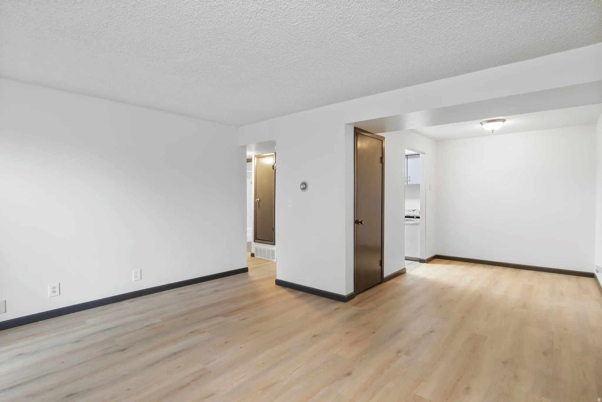 Empty room with a textured ceiling and light wood-type flooring