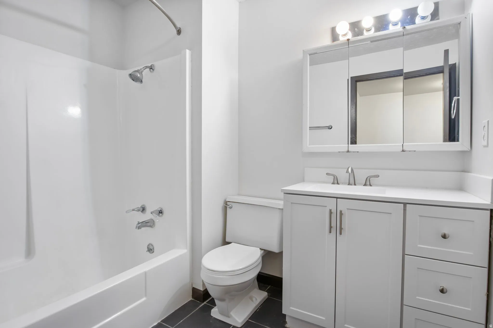 Full bathroom featuring vanity, shower / washtub combination, and dark tile patterned flooring