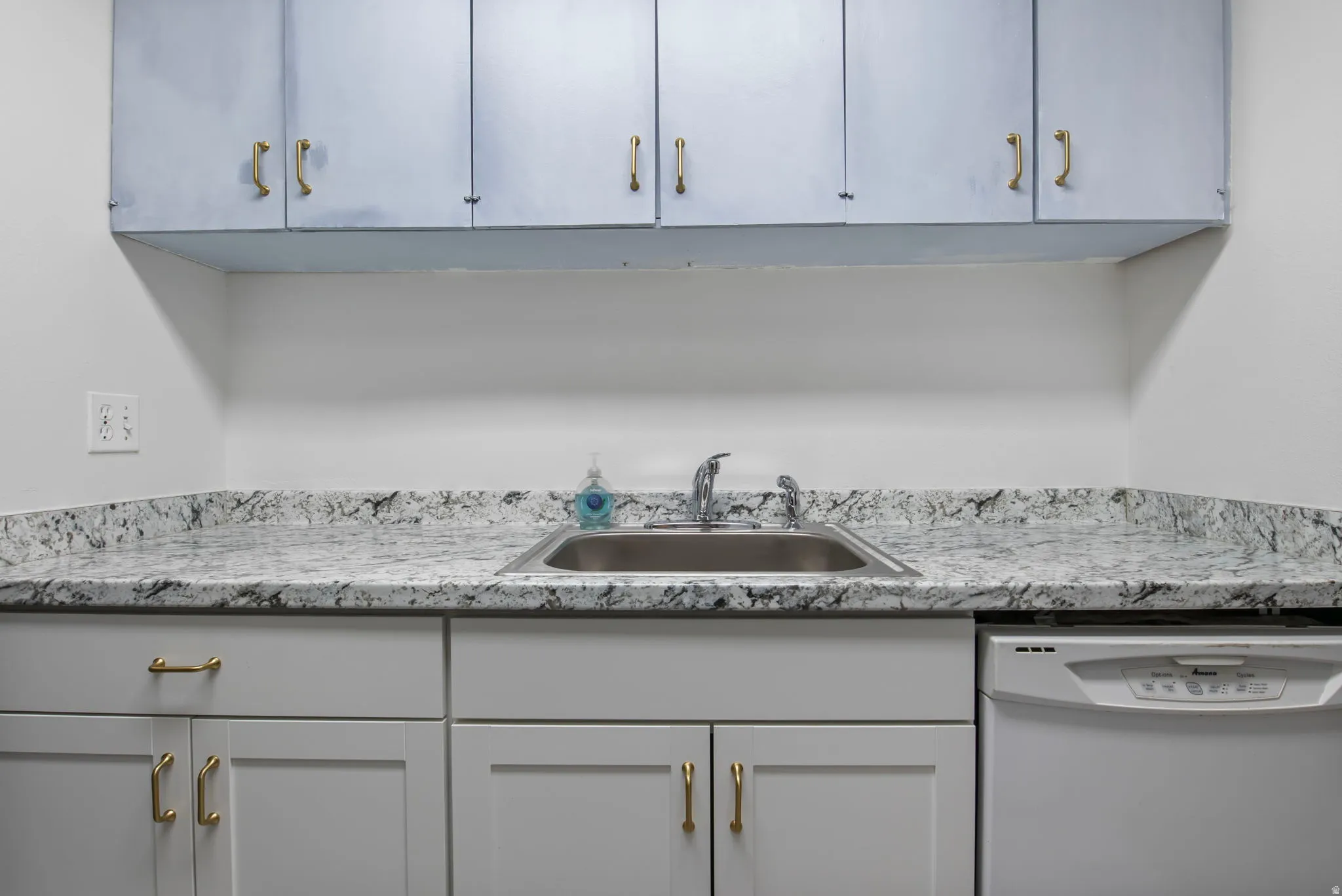 Kitchen with dishwasher and light stone counters