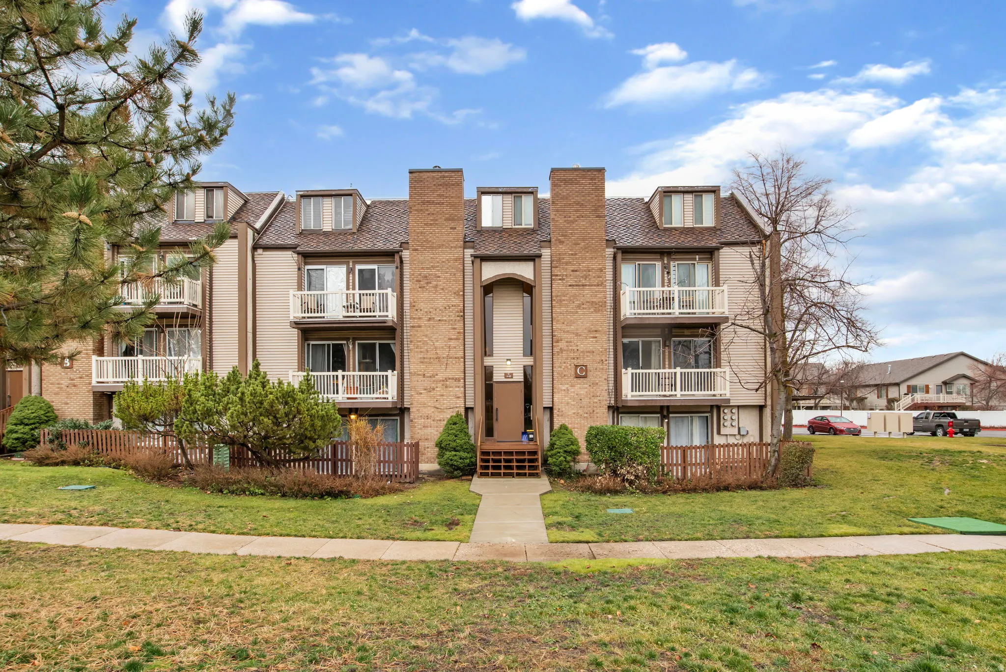 View of front of home featuring a front yard, brick siding, and a balcony