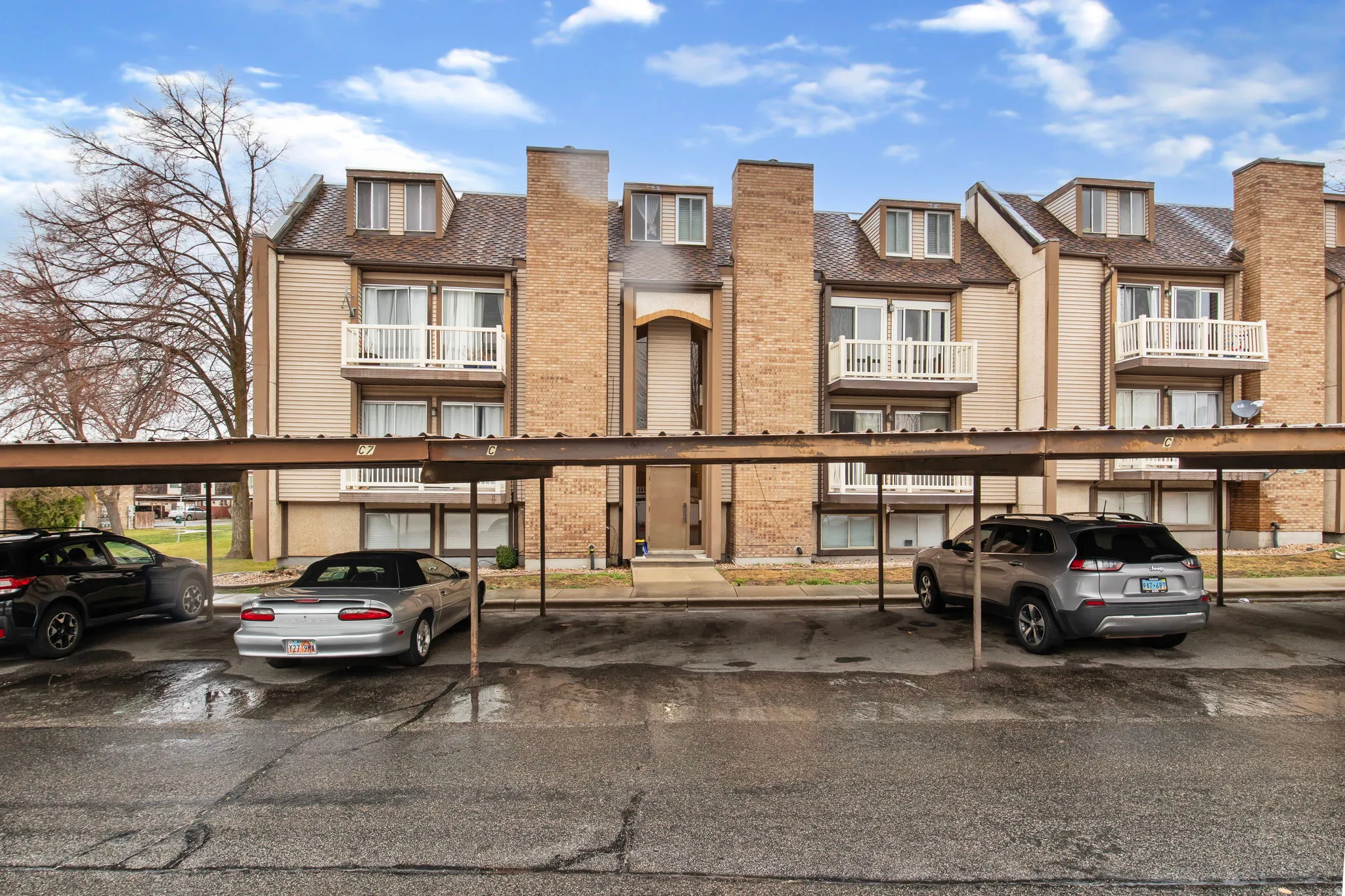 View of front facade featuring covered parking and brick siding