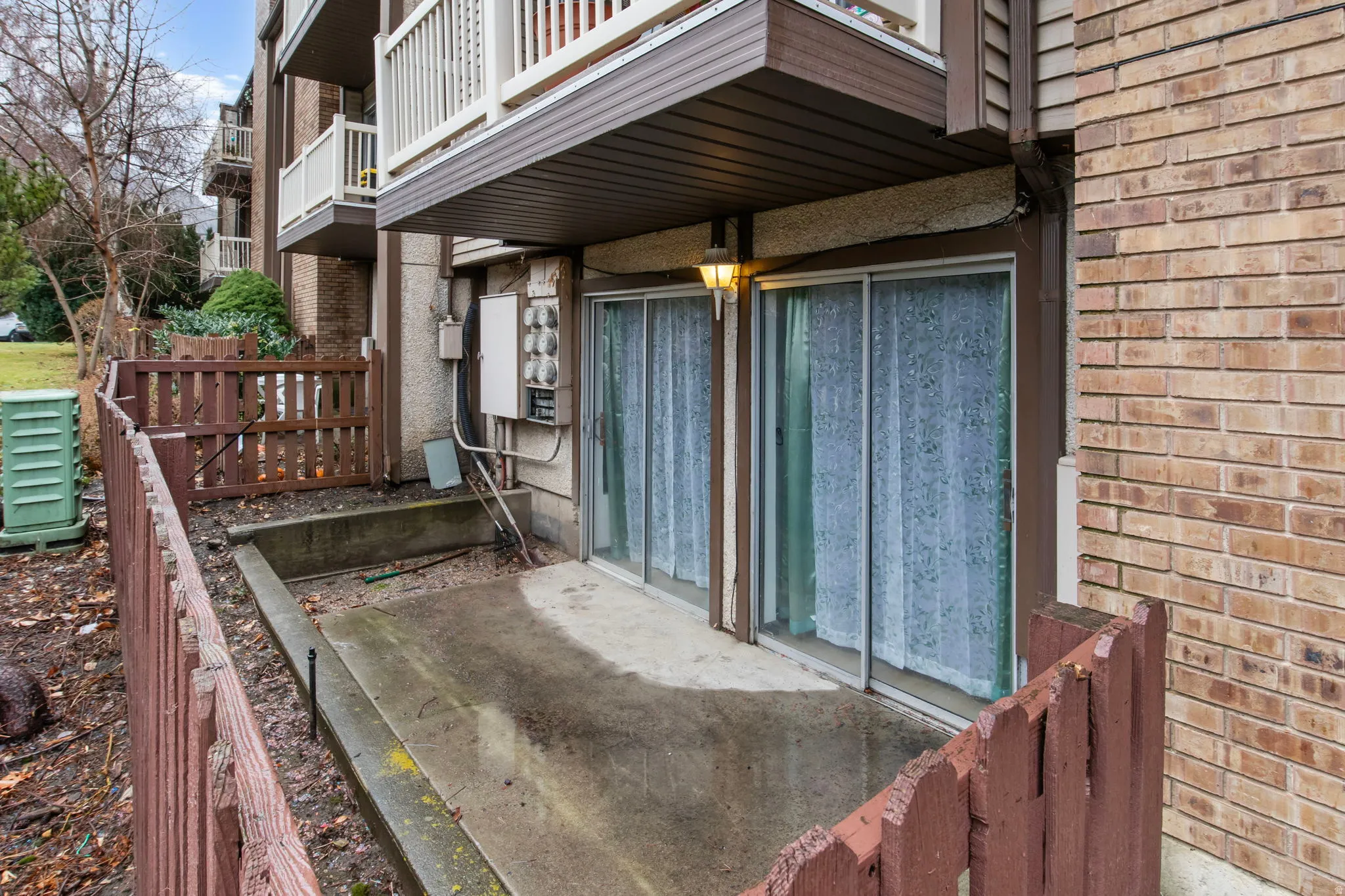 View of side of property with brick siding, a patio area, and a balcony