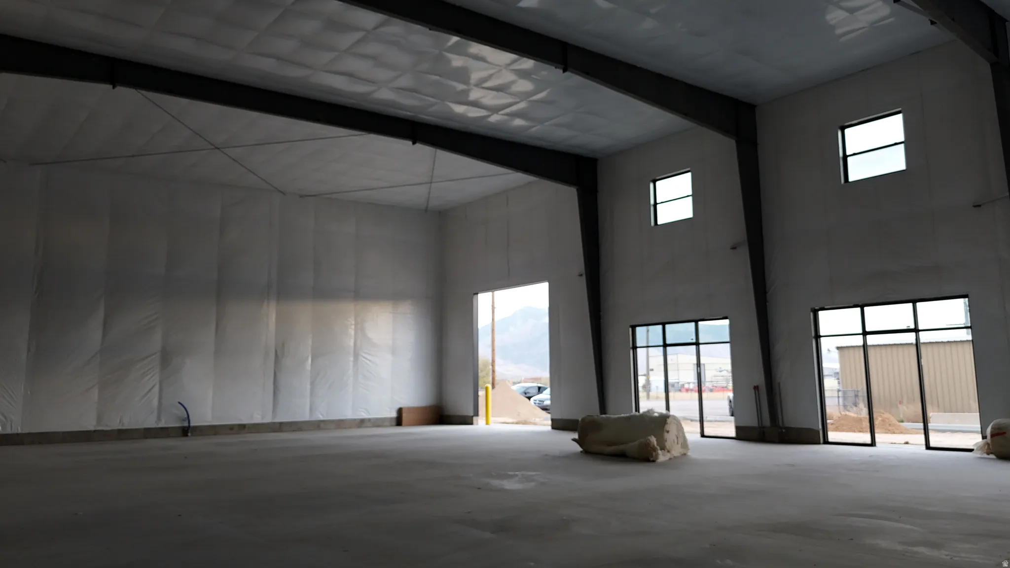 Miscellaneous room featuring a high ceiling, unfinished concrete floors, plenty of natural light, and beam ceiling