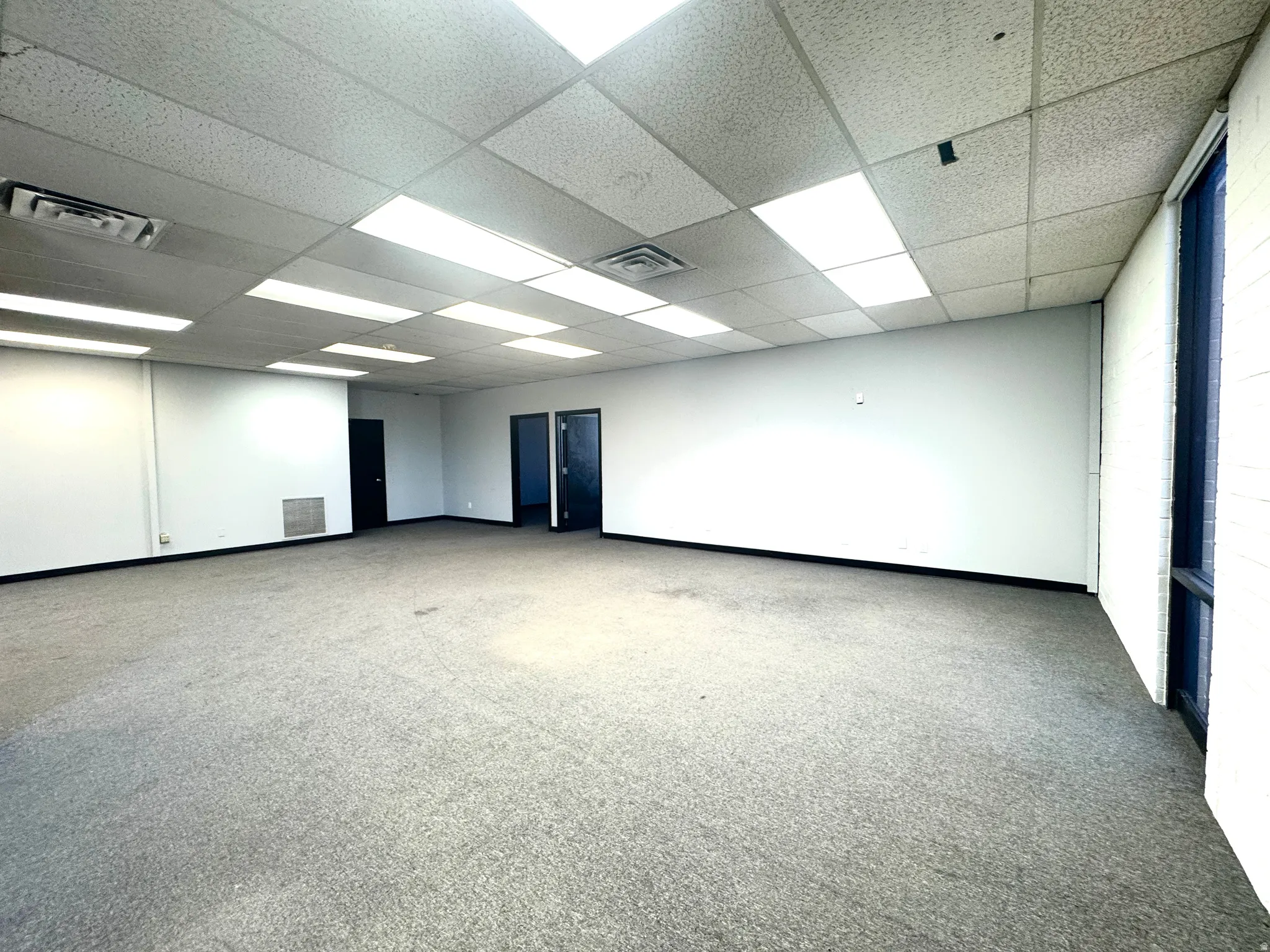 Unfurnished room featuring light carpet and a paneled ceiling