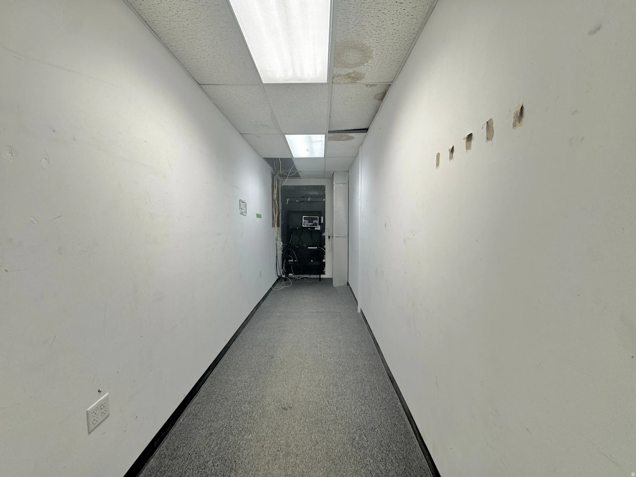 Hall with a paneled ceiling and baseboards