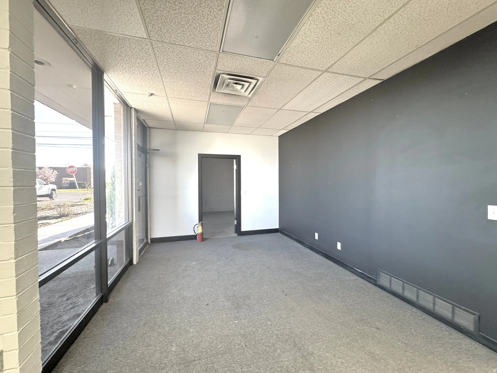 Empty room featuring a paneled ceiling and dark carpet