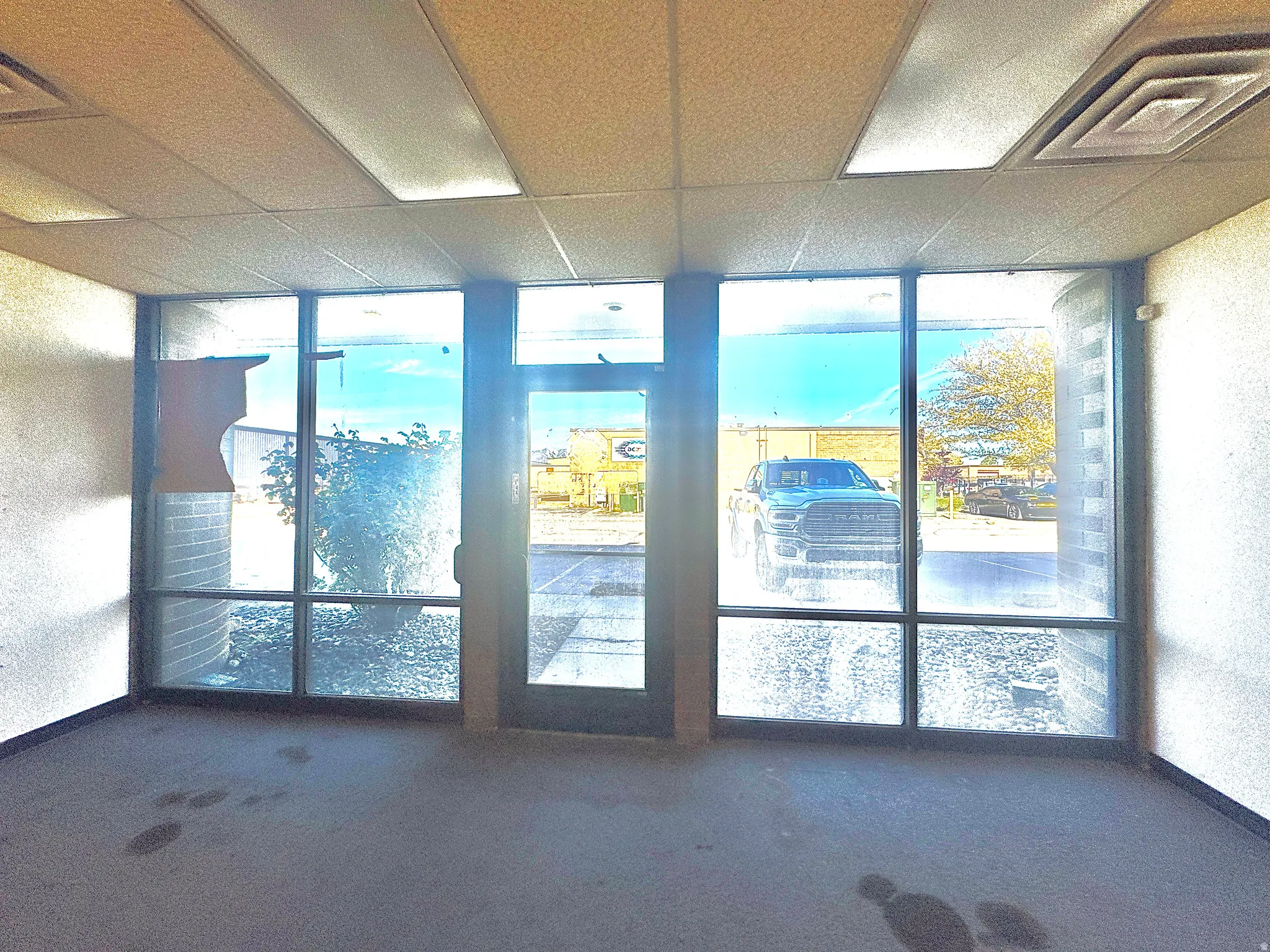 Doorway to outside featuring a textured wall, carpet flooring, floor to ceiling windows, and a paneled ceiling