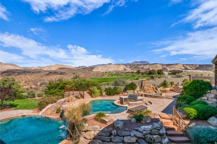 View of pool with a patio area, a mountain view, a water slide, and a hot tub