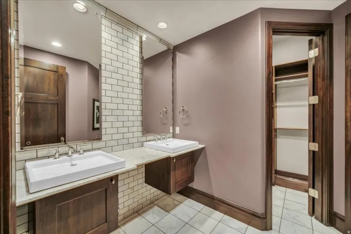 Bathroom featuring double vanity, tasteful backsplash, a walk in closet, recessed lighting, and light tile patterned floors
