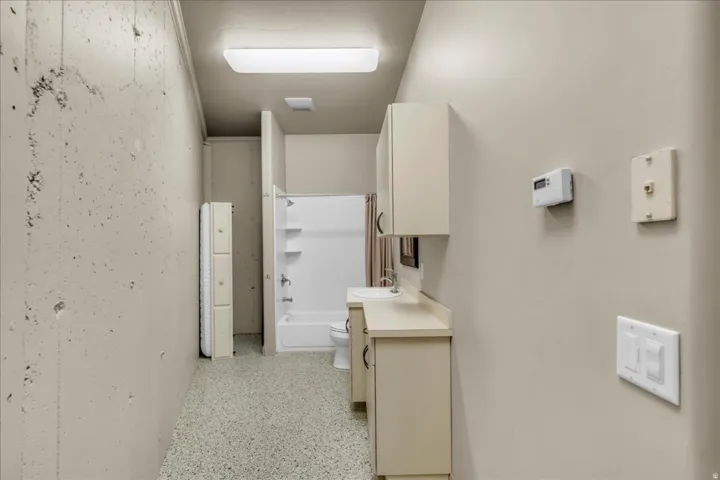 Corridor with dark aggregate flooring and a sink