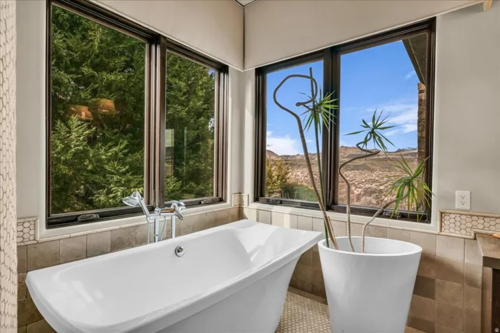 Bathroom with tile walls, a soaking tub, wainscoting, and tile patterned flooring