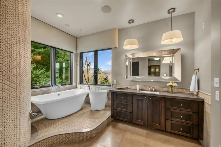 Full bathroom featuring tile walls, a wainscoted wall, vanity, a freestanding bath, and light tile patterned floors