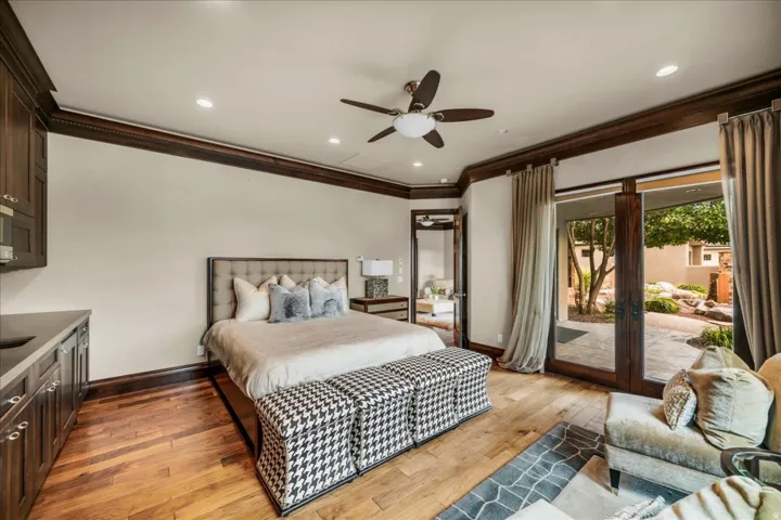 Bedroom featuring ornamental molding, light wood-type flooring, access to outside, a ceiling fan, and french doors
