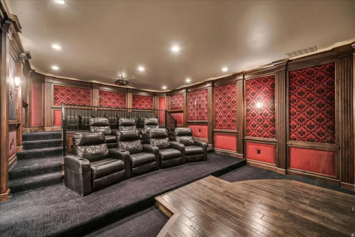 Cinema room with a decorative wall, dark wood finished floors, crown molding, and recessed lighting
