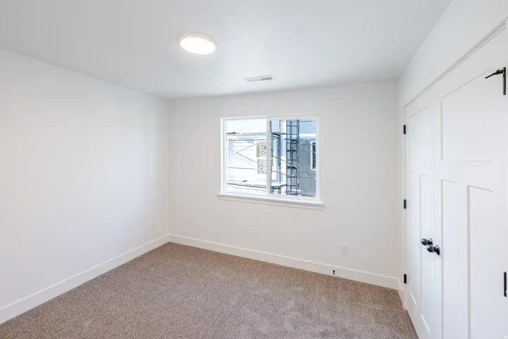 Carpeted room featuring a single window, recessed lighting, and a white paneled door with black hardware